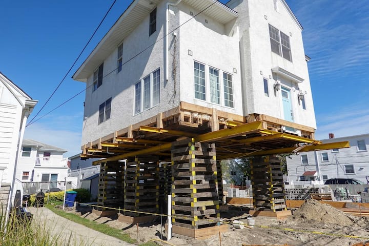 A team of professionals using specialized equipment to raise a house in Lawrence, preparing it for elevation and renovation